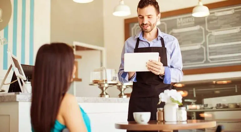 Waiter taking an order on a tablet with AxoOne restaurant TAB ordering software in Riyadh
